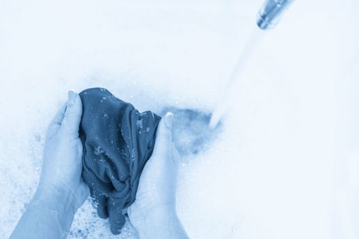 Female hands washing color clothes in basin