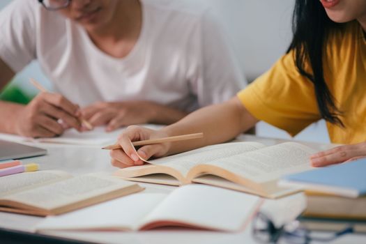 Young woman and man studying for a test or an exam. Tutor book with friends. Young students campus or classmates helps friend catching up workbook and learning tutoring in classroom, teaching, learning