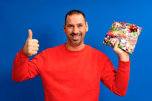 The best gift. Happy man holds a gift showing thumb up. Gift or gift box. Celebrating birthday anniversary. Special occasion. Preparation and celebration of holidays.