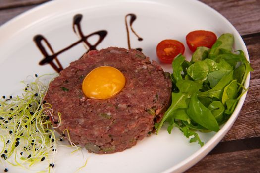 Steak Tartare with vegetables salad and french fries on dish. High quality photo