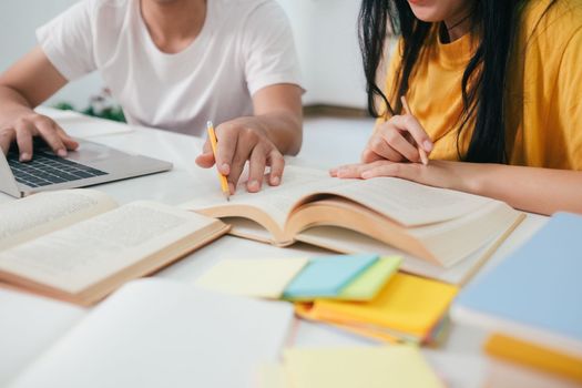 Young woman and man studying for a test or an exam. Tutor book with friends. Young students campus or classmates helps friend catching up workbook and learning tutoring in classroom, teaching, learning