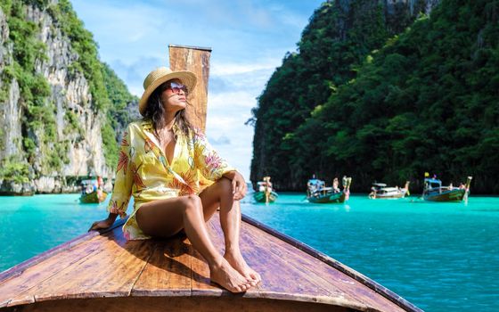 Asian women in front of a longtail boat at Kho Phi Phi Thailand, women in front of a boat at Pileh Lagoon