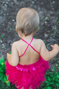 Cute baby in a swimsuit plays in the yard.