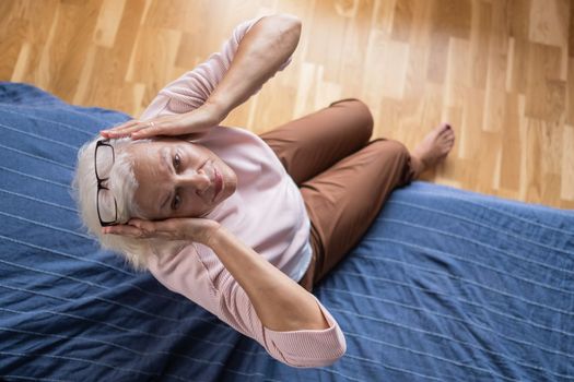 Senior caucasian woman suffering from a headache resting at home on sofa