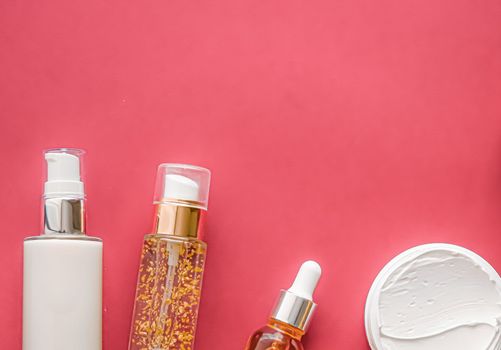Beauty cosmetics and skincare product on coral background, flatlay.