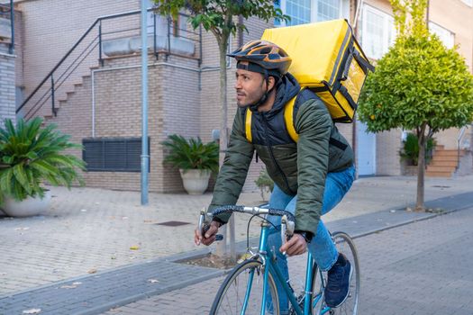 Young African American delivery man riding on bike. Black courier delivering food and drink in town outdoors on stylish bicycle. High quality photo