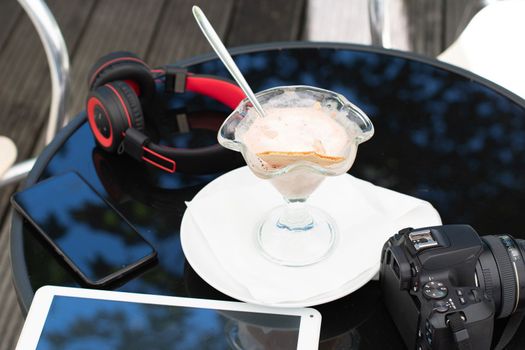 tables in a cafe melted ice cream in a bowl near the phone headphones and a tablet. High quality photo