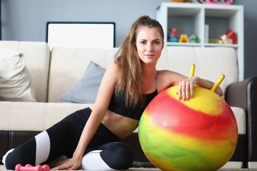 Beautiful smiling lady exercising at home on fitball. Resting after dynamic home workout concept