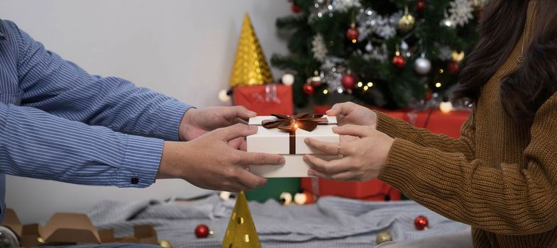 Happy woman giving Christmas and New Year Gift box to woman at Home.Family Xmas celebration. Christmas decoration. Relationship..