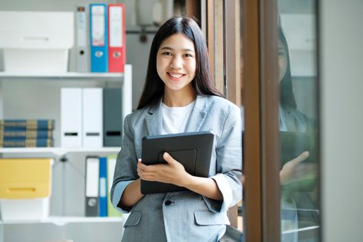 Young asian businesswoman uses a laptop to contact a customer, working hard at the office using laptop data graphs, planning for improvement, analyzing and strategizing for business growth. Business concept