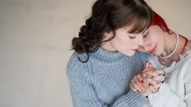 Portrait of two tenderly hugging women dressed in sweaters. Lesbian intimacy