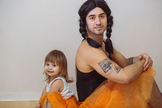 Father and little girl are wearing matching ballerina dresses. 
