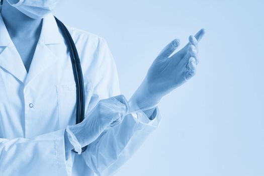 Close up of a female doctor putting latex gloves on a white background