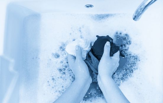 Female hands washing color clothes in basin