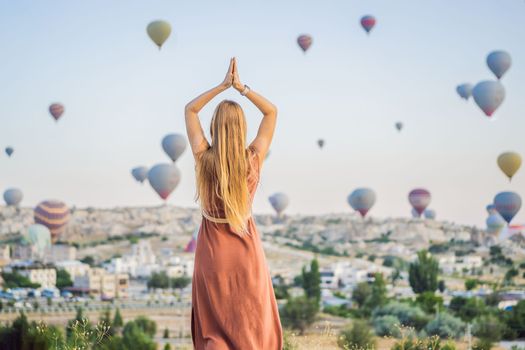 Tourist woman looking at hot air balloons in Cappadocia, Turkey. Happy Travel in Turkey concept. Woman on a mountain top enjoying wonderful view.