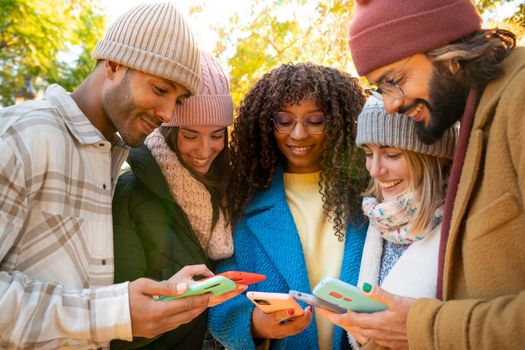 Group of young multi-ethnic friends using cell phones outdoors. Concept of community millennial people addicted to technology. Social Media communication generation Z