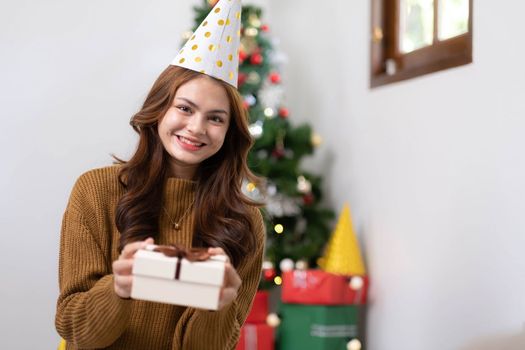 Merry Christmas and Happy Holidays Young woman with a beautiful face in a yellow shirt shows joy with gift boxes in a house