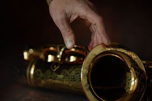 the hands of a musician on the saxophon - an ancient musical wooden instrument popular in classical brass marching jazz folk music, loved by children and adults, amateurs and professionals.. High quality photo