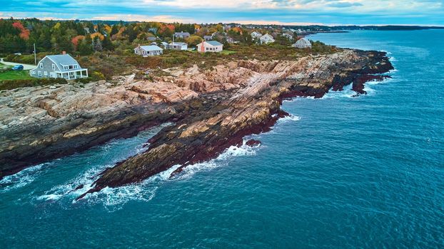 Image of Aerial of coast of Maine with rocky cliffs, houses, and ocean waves crashing