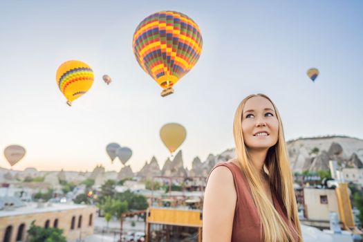 Tourist woman looking at hot air balloons in Cappadocia, Turkey. Happy Travel in Turkey concept. Woman on a mountain top enjoying wonderful view.