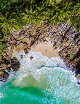 Drone aerial view at Freedom beach in Phuket Thailand, men laying down on a beach in bay at Phuket
