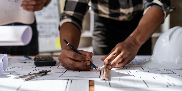 Architect team working with blueprints for architectural plan, engineer sketching a construction project, green energy concept.