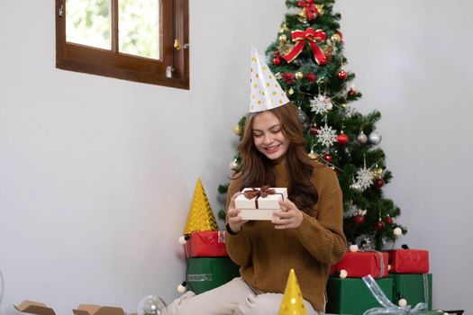 Merry Christmas and Happy Holidays Young woman with a beautiful face in a yellow shirt shows joy with gift boxes in a house