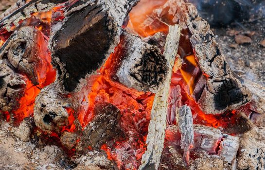 scorched wood and glowing coal in the fire. orange glowing coal. Smoldering glowing afterburning embers on the fire.