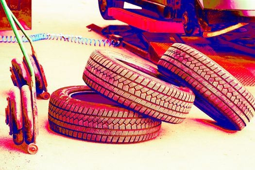 Red neon replacing a car wheel at a tire station. a rubber covering, typically inflated or surrounding an inflated inner tube, placed around a wheel to form a flexible contact with the road.