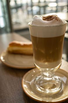 Big cappuccino glass coffee with a cream sugar bun in a restaurant.Morning breakfast or after lunch concepts.