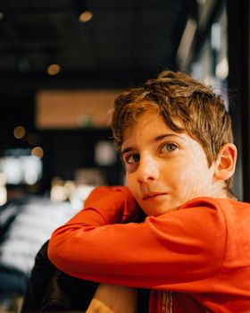 Portrait of a cute young boy looking at camera and smiling indoors low light.