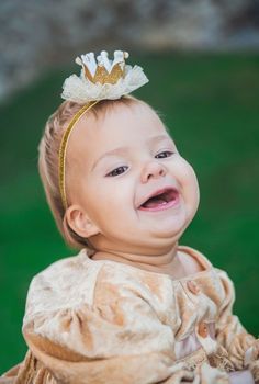 charming baby in princess costume with a crown on head is laughs.