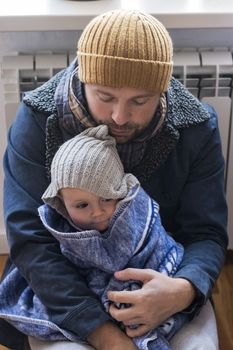 Man wearing warm clothing feeling cold checking central heating battery. Energy crisis in Europe