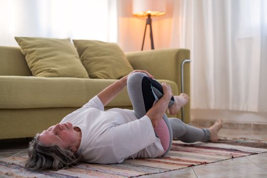 senior woman doing warmup workout at home. Fitness woman doing stretch exercise stretching her body. Elderly woman living an active lifestyle. 