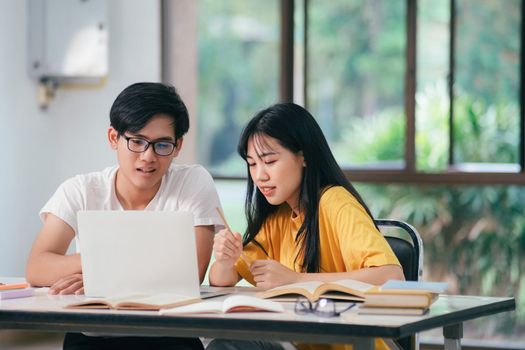 Young woman and man studying for a test or an exam. Tutor book with friends. Young students campus or classmates helps friend catching up workbook and learning tutoring in classroom, teaching, learning