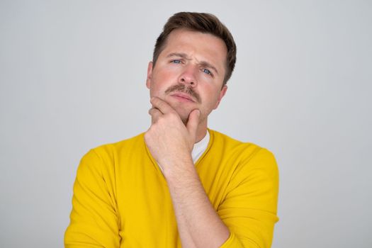 Thoughtful caucasian young man touch chin with finger thinking or considering, pensive European man making decision or imagining