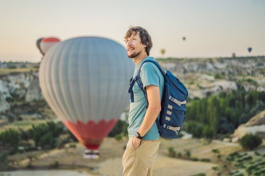 Tourist man looking at hot air balloons in Cappadocia, Turkey. Happy Travel in Turkey concept. Man on a mountain top enjoying wonderful view.
