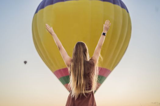 Tourist woman looking at hot air balloons in Cappadocia, Turkey. Happy Travel in Turkey concept. Woman on a mountain top enjoying wonderful view.