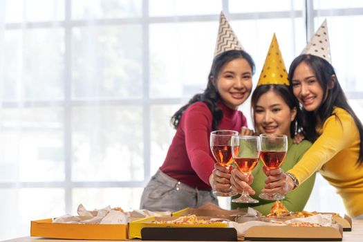 Group of happy young Asian people with friends celebrating clinking glasses during dinner party.