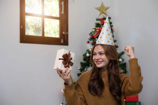 Merry Christmas and Happy Holidays Young woman with a beautiful face in a yellow shirt shows joy with gift boxes in a house