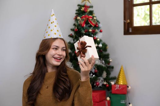 Merry Christmas and Happy Holidays Young woman with a beautiful face in a yellow shirt shows joy with gift boxes in a house