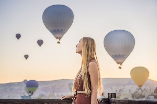 Tourist woman looking at hot air balloons in Cappadocia, Turkey. Happy Travel in Turkey concept. Woman on a mountain top enjoying wonderful view.