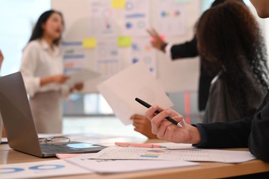 Cropped image of businessman analyzing financial data, stock market information while sitting at meeting table.