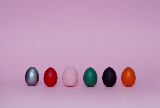 Six assorted ornamental hand painted eggs stand on paper background. Easter composition.