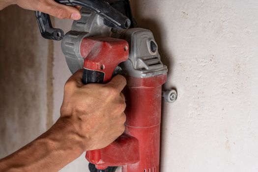 professional construction power tool for cutting strob in the hands of a worker during the renovation of the apartment. A hand-held power tool with two diamond discs for cutting grooves in the wall for laying electrics. Professional tool. Close-up