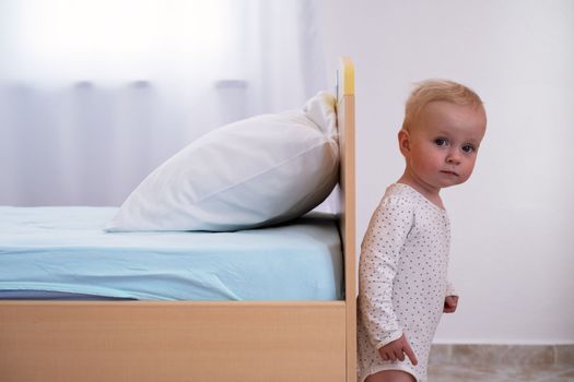 Caucasian baby girl playing hide and seek with her parents hiding above the bed