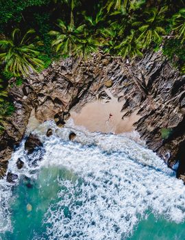 Drone aerial view at Freedom beach in Phuket Thailand, men laying down on a beach in bay at Phuket