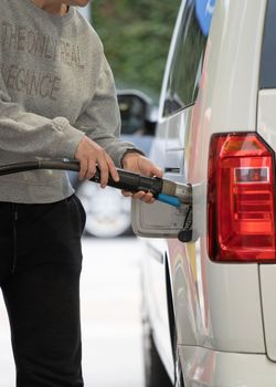 Woman fills natural gas into her car at a gas station.