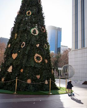 Little kid playing with scooter around christmas tree in Madrid city center.