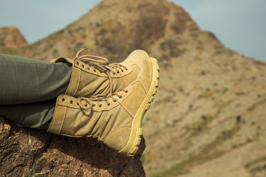 Close-up of traveler female legs with hiking boots relaxing on the rock during trekking.